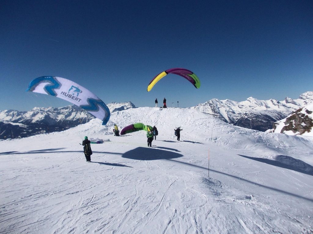 People landing on a snowy mountain after paragliding