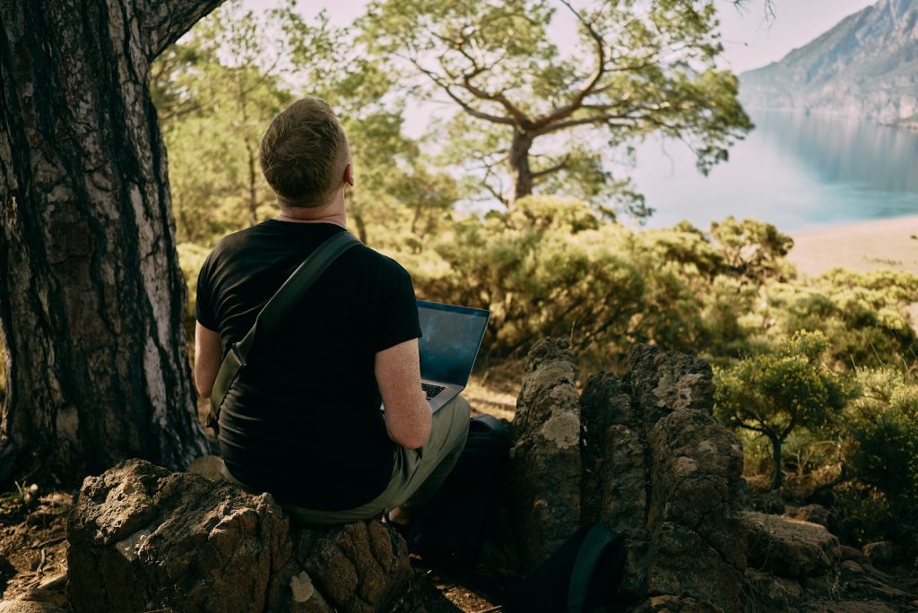 a man working on a laptop in a forest