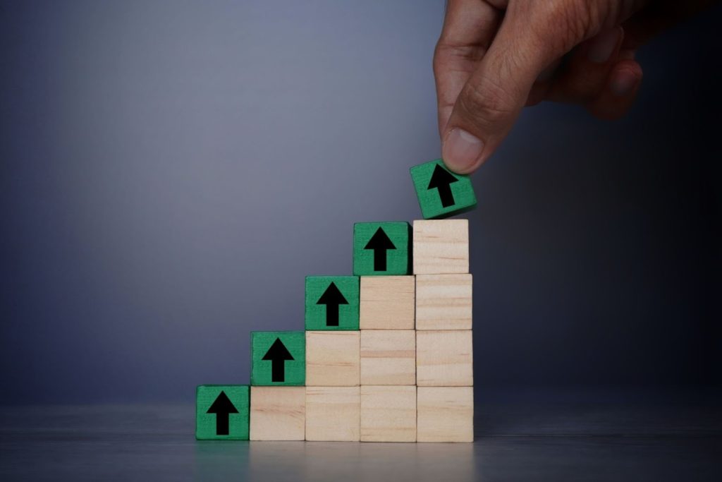 a hand putting a green wooden cube with an upward arrow sign